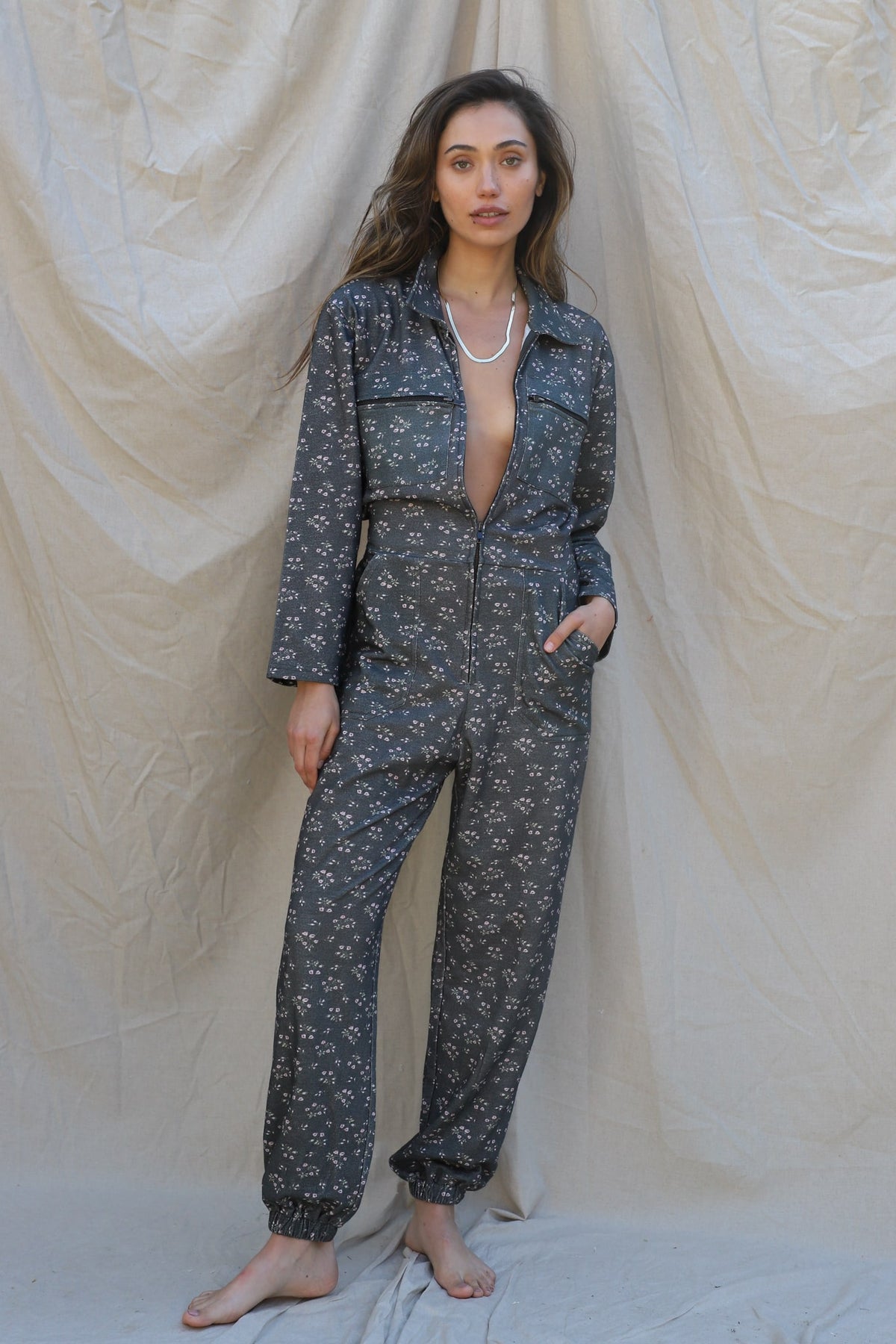 zip up long sleeve jumpsuit in washed black with allover floral print. Dual breast pockets, hip pockets, back pockets, and collared neckline