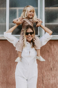 adult wearing palmetto station suit in white. Child wearing little palmetto station suit in dusty pink